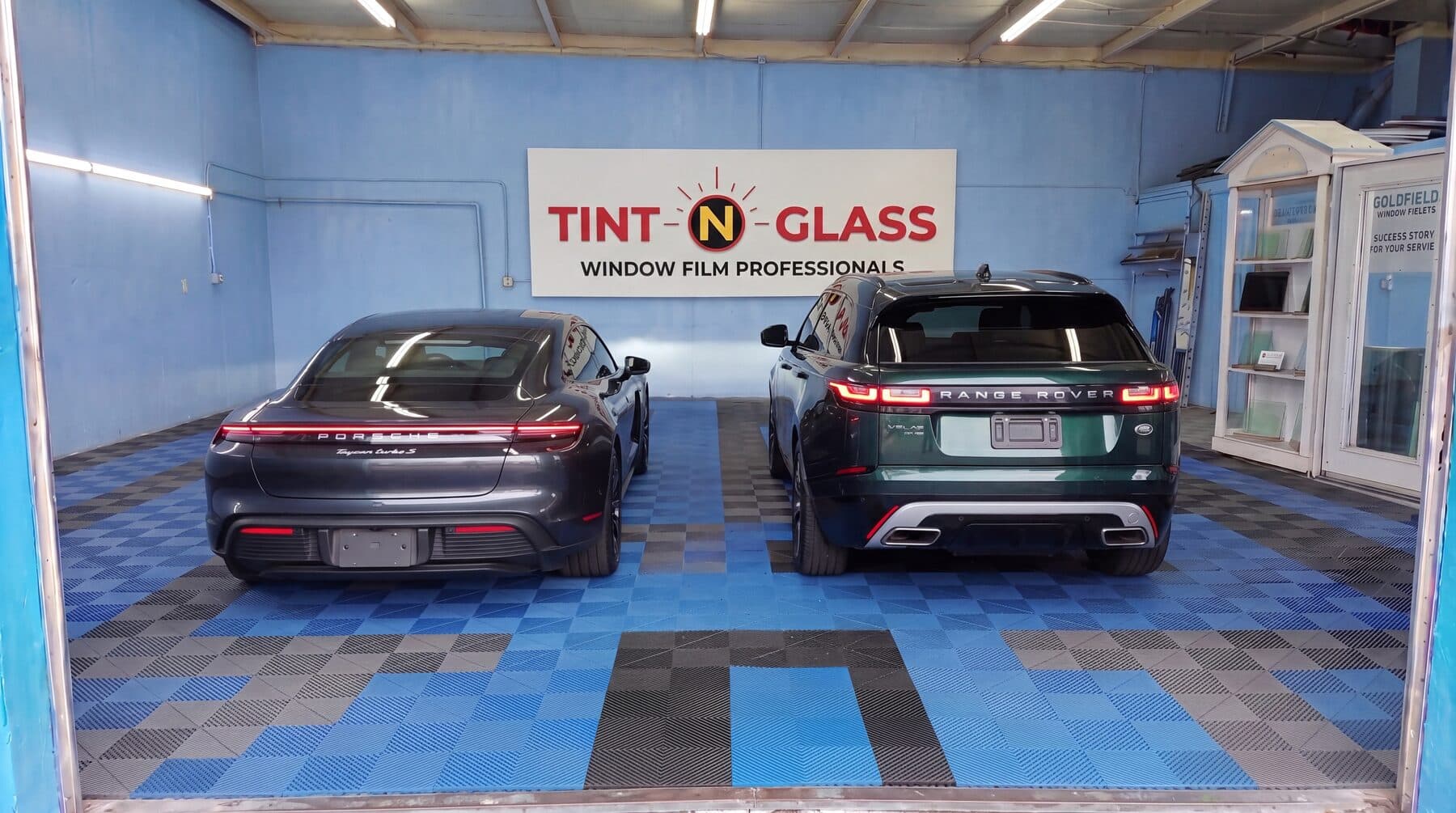 Two freshly tinted vehicles lined up inside the shop.